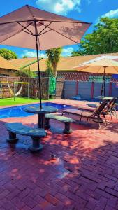 a picnic table with an umbrella next to a pool at Little Haven! in Rustenburg