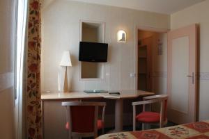 a room with a desk with a television and chairs at Hotel Des Bains in Lancieux