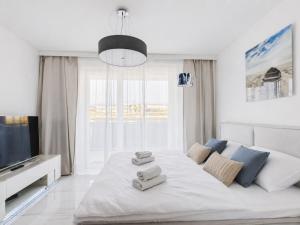 a white bedroom with a large bed with towels on it at BelMare Seaside Apartment by Solarento in Międzyzdroje