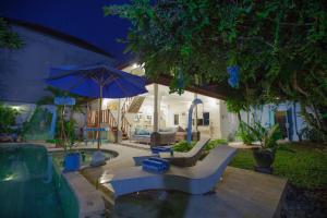 eine Terrasse mit Stühlen und einem Sonnenschirm bei Nacht in der Unterkunft Villa Alam Biru Gardenia in Seminyak