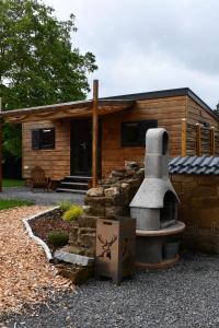 a log cabin with a stone oven in front of it at Peryton Houses -Chalets zum Wohlfühlen in Sinsheim