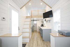 a kitchen with white walls and a staircase in a tiny house at River and Twine in Rocky Mount