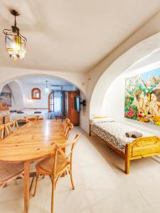 a dining room with a wooden table and a bed at El Beaterio Apartments in Tarifa