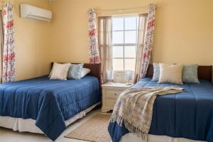 a bedroom with two beds and a window at Pink Sands-At Bel Air in Saint Philip