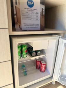 an open refrigerator with drinks and soda cans in it at Hotel SMA in Puerto Iguazú