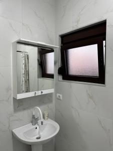 a white bathroom with a sink and a mirror at Laki in Donji Štoj
