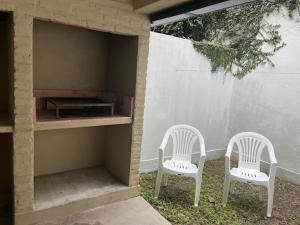 two white chairs sitting next to a building at Yerba Buena House in Yerba Buena