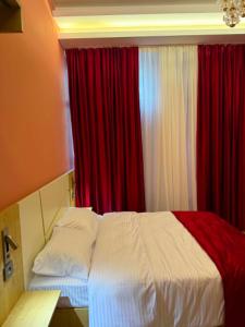 a bedroom with a white bed with red curtains at Three Colour Rooms in Kutaisi