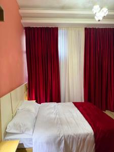 a bedroom with a large bed with red curtains at Three Colour Rooms in Kutaisi