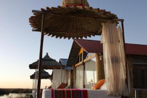 two umbrellas on top of a table in front of a building at Uros Titicaca Aru Lodge in Puno