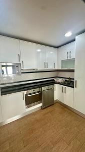 a kitchen with white cabinets and stainless steel appliances at Aqui é o seu lugar. in Bobadela +5 photos