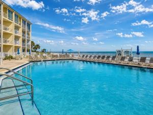 a swimming pool at a resort with chairs and the ocean at Ocean East Resort Club in Ormond Beach +20 photos