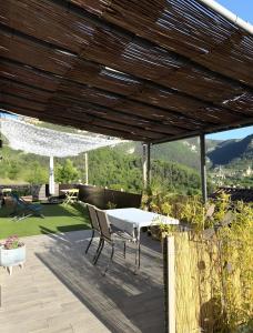 a patio with a table and chairs under a wooden roof at Appartement Gorges du Tarn in Mostuéjouls