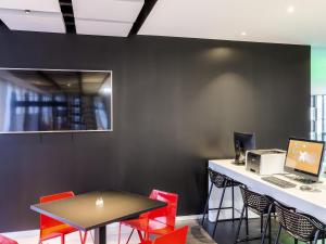 an office with red chairs and a desk with a laptop at ibis Styles Basel City in Basel