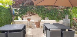 a patio with two tables and an umbrella at Maison Brunetière in Saint-Martin-lʼArs