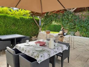 a table and chairs under an umbrella on a patio at Maison Brunetière in Saint-Martin-lʼArs