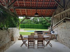 a patio with a table and chairs and a grill at Maison Brunetière in Saint-Martin-lʼArs