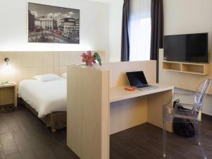 a hotel room with a bed and a desk with a laptop at Ibis Styles La Louvière in La Louvière