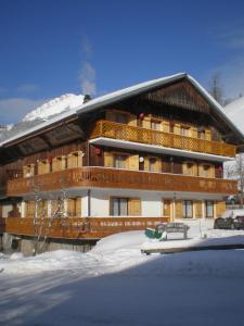 um grande edifício com neve em frente em CHAMBRE d'HÔTE LA PETITE BERGERIE em La Chapelle-dʼAbondance