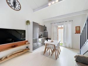 a living room with a table and a clock on the wall at Maison village accès mer et commerces à pieds in Le Barcarès