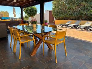 a glass table and yellow chairs on a patio at Los Jazmines in Agaete
