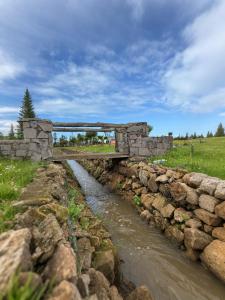 a stone bridge over a stream in a field at Chalet en Pierre Benslimane in Aïn Sferjila