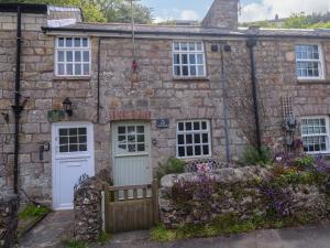 an old stone house with white doors and windows at May Cottage in Pentewan
