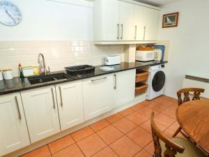 a kitchen with white cabinets and a table at May Cottage in Pentewan