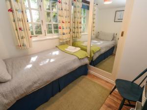 a small room with two beds and a mirror at May Cottage in Pentewan