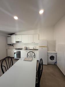 a kitchen with white cabinets and a table and chairs at Chiara 5 in Cairo Montenotte