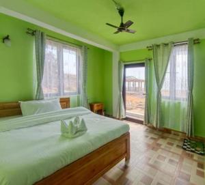 a bedroom with green walls and a bed with a fan at La Murphy Homestay in Cherrapunji