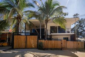 a house with two palm trees behind a fence at Hakuna in San Juanillo