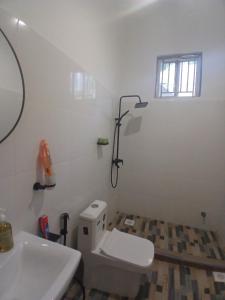 a bathroom with a white toilet and a sink at Sun House Kendwa in Kendwa