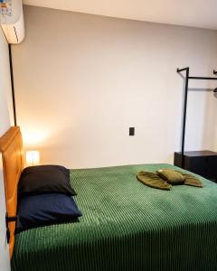 a bedroom with a bed with a green comforter at AP Central Aconchegante 03 Quartos Próx Unimed Com Garagem, Ar Quente Frio, Cozinha Completa - Até 06 Pessoas in Chapecó