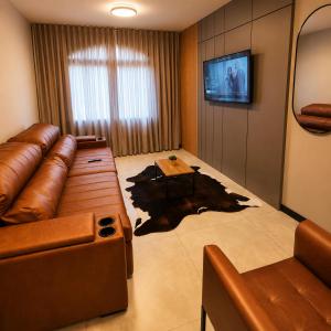 a living room with a leather couch and a table at AP Central Aconchegante 03 Quartos Próx Unimed Com Garagem, Ar Quente Frio, Cozinha Completa - Até 06 Pessoas in Chapecó