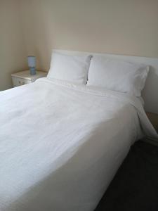 a white bed with white sheets and pillows at Milton Keynes Lettings in Milton Keynes