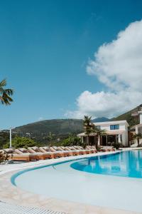 a swimming pool with lounge chairs and a building at Vila Milo in Himare