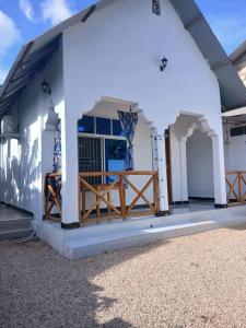 a white building with blue windows and a porch at Sun House Kendwa in Kendwa
