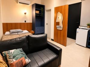 a living room with a leather couch and a bed at Studio Moderno e Novo - Cozinha Completa, Ar Condicionado e Wifi - Rápido Acesso ao Centro in Chapecó