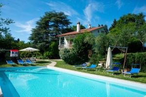 a swimming pool with chairs and a house at Villa Cassiani in Fiorenzuola di Focara