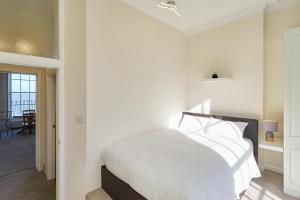 a bedroom with a white bed and a dining room at Coastal charm in Herne Bay