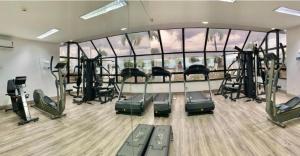 a gym with cardio equipment and a large glass wall at Flat no Hotel Millenium Manaus in Manaus