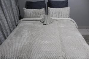 a bed with a white comforter and pillows at Penthouse in Bloemfontein