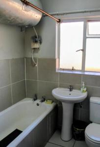 a bathroom with a sink and a tub and a toilet at Penthouse in Bloemfontein +14 photos