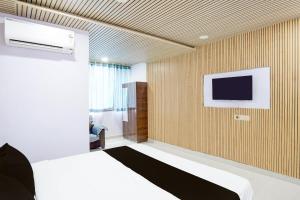 a bedroom with a bed and a tv on a wall at Super Hotel O Sunshine Classic in Nagpur