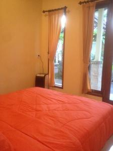 een slaapkamer met een oranje bed en 2 ramen bij Artawa House in Ubud