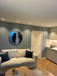 a living room with a white couch and a mirror at Nyoppusset hybelleilighet in Bjørkheim