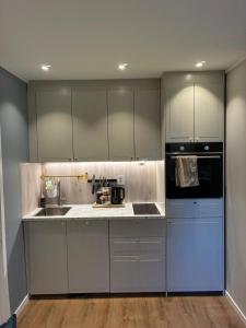 a kitchen with white cabinets and a sink and a stove at Nyoppusset hybelleilighet in Bjørkheim