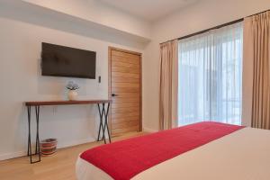 a bedroom with a bed and a television on a wall at Hotel Fusión in Puerto Escondido