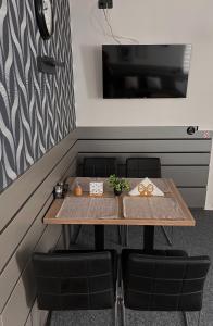 a table with chairs and a tv on a wall at Apartmán Majerův dvůr in Rožnov pod Radhoštěm